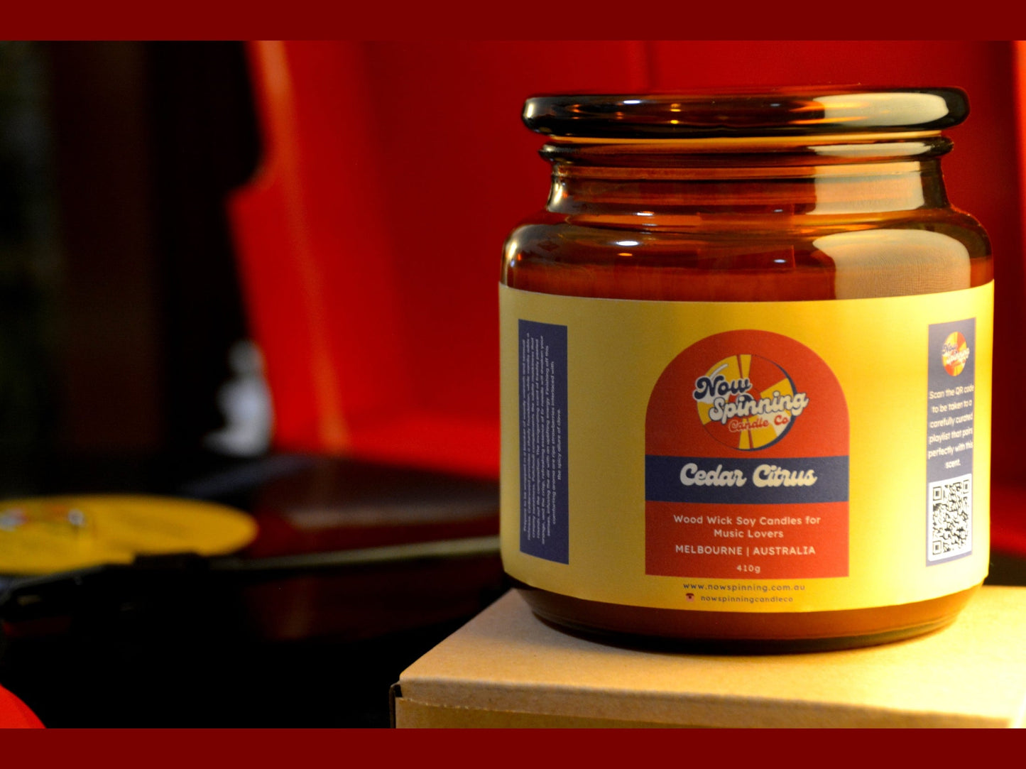 Jar of candle with a colorful label on a wooden surface against a blurred background