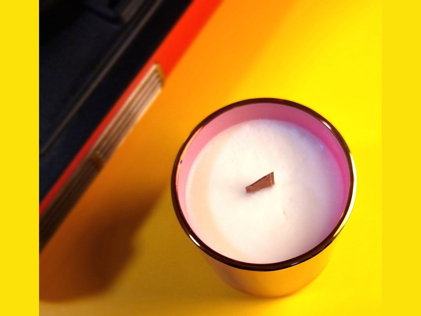 Candle in a glass holder on a yellow surface with a Record Player beside it