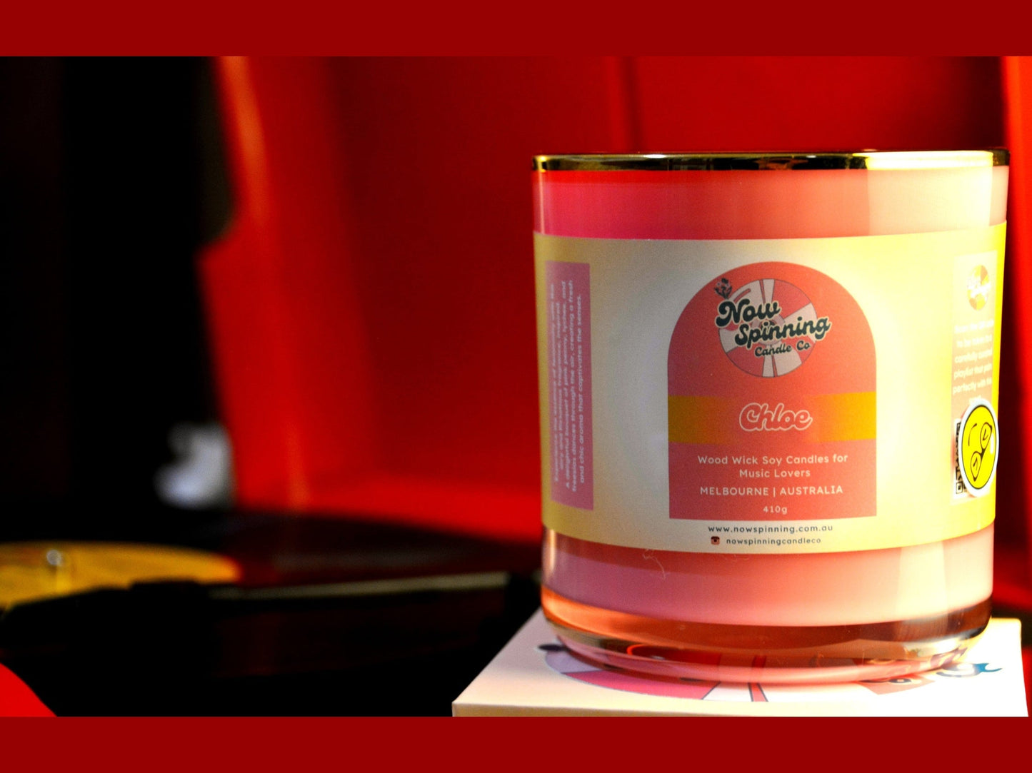 Candle in a glass jar with a label on a red background