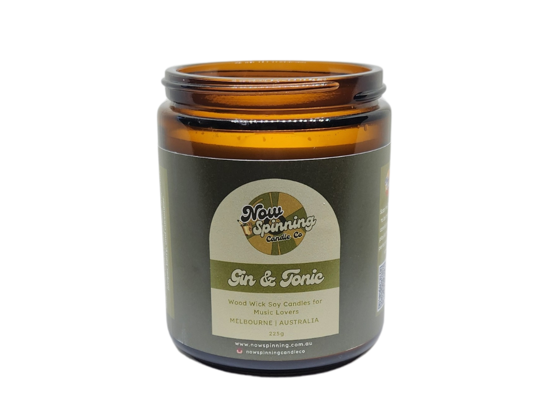 Gin & Tonic candle with a background of a amber glass jar and a black screw top lid.