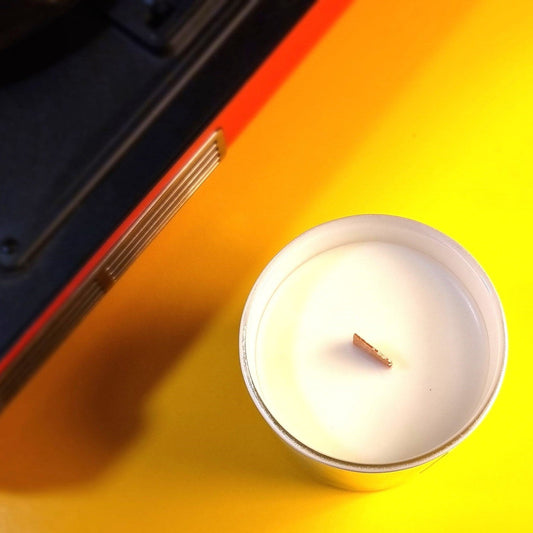 Candle on a yellow surface with a red and black object partially visible