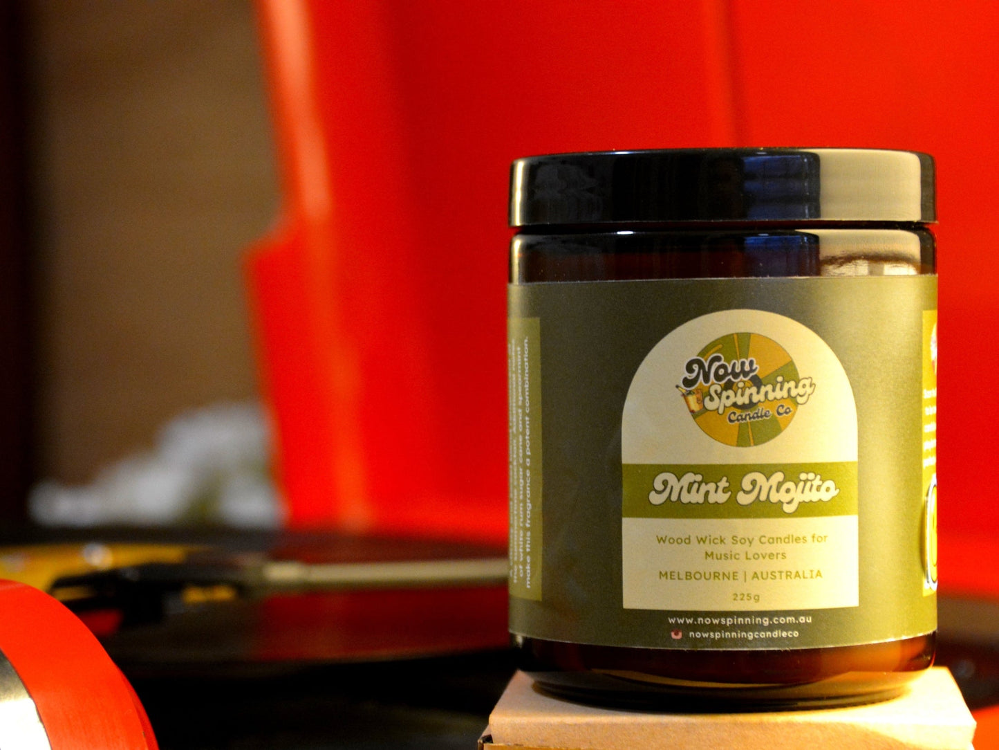 Mint Mojito candle with a label on a wooden surface against a red record player