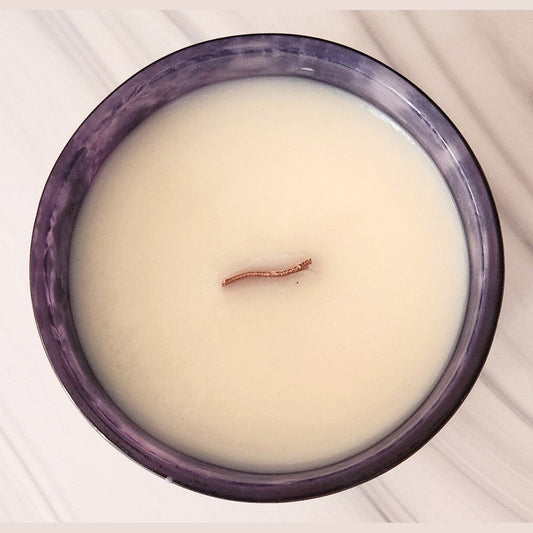 Candle with a small wood wick on top in a purple container