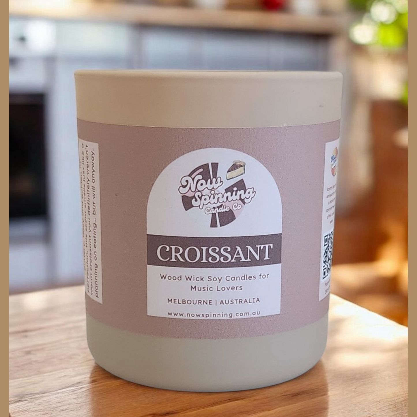 Candle jar labeled 'Croissant' on a wooden surface with a blurred kitchen background