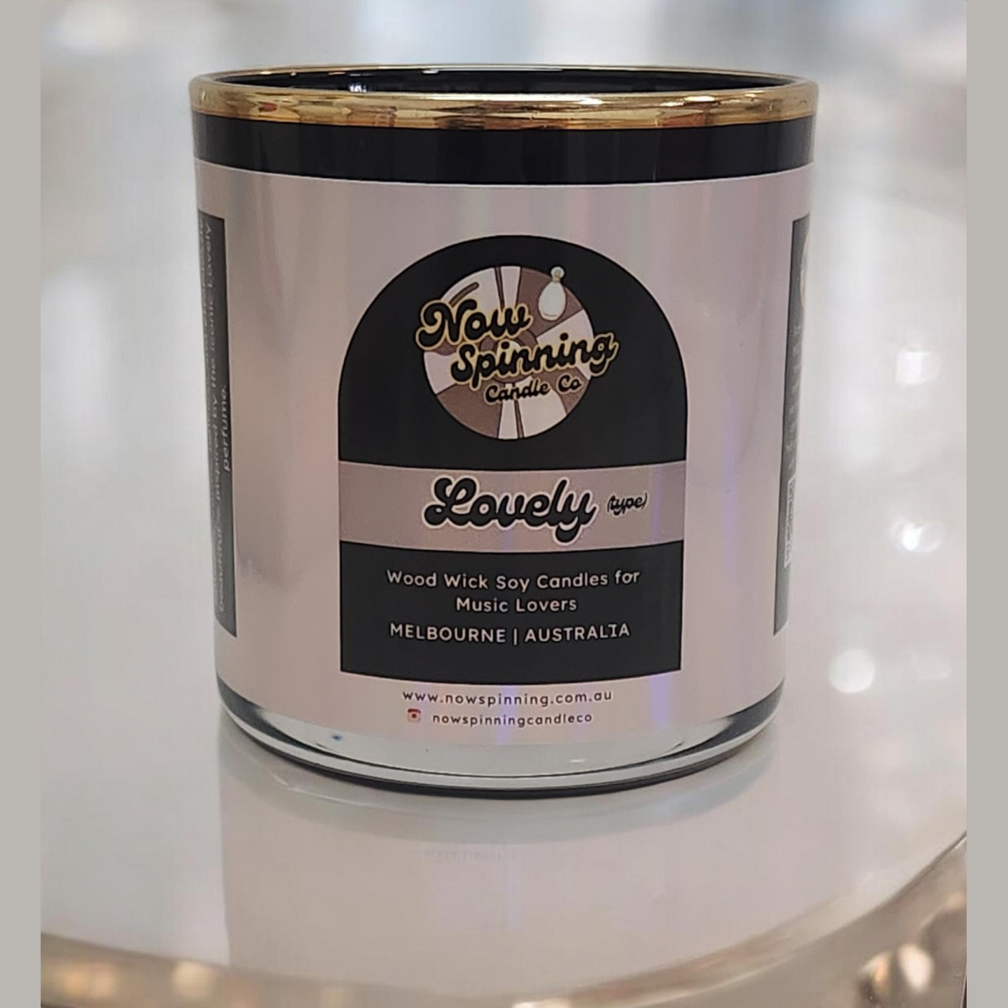 Candle in a glass jar with a label on a reflective surface
