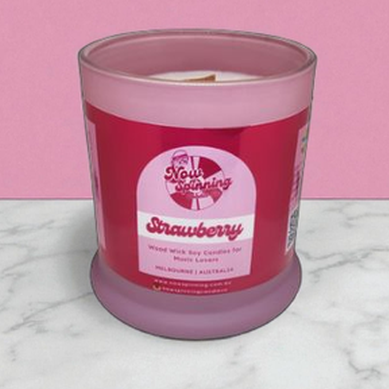 Pink candle with a label on a marble surface and pink background