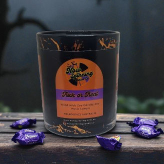 Candle with a label on a wooden surface with purple wrappers.