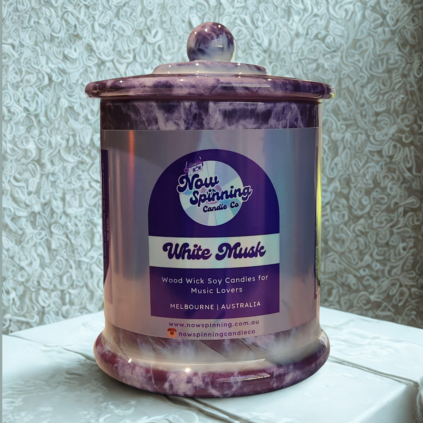 Candle jar with a label on a textured surface