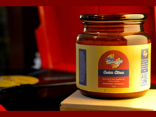 Jar of candle with a colorful label on a wooden surface against a blurred background
