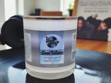 Candle labeled 'Cool Water' on a turntable with a blurred background