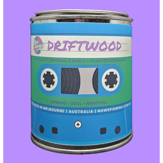 A cylindrical metal tin styled like a retro cassette tape, labeled 'DRIFTWOOD' by Nowspinning, set against a solid lavender background.