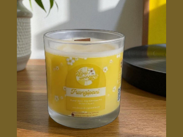 Glass candle with a yellow label on a wooden surface