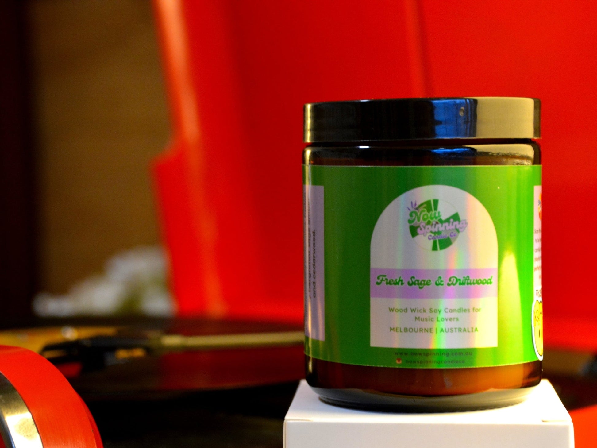 Jar with a green label on a white stand against a red record player
