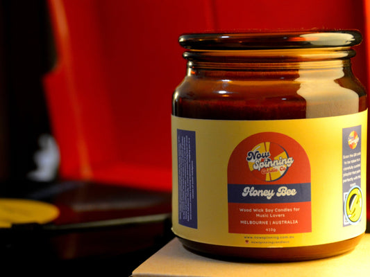 Honey Bee Candle with a label on a next to a record player