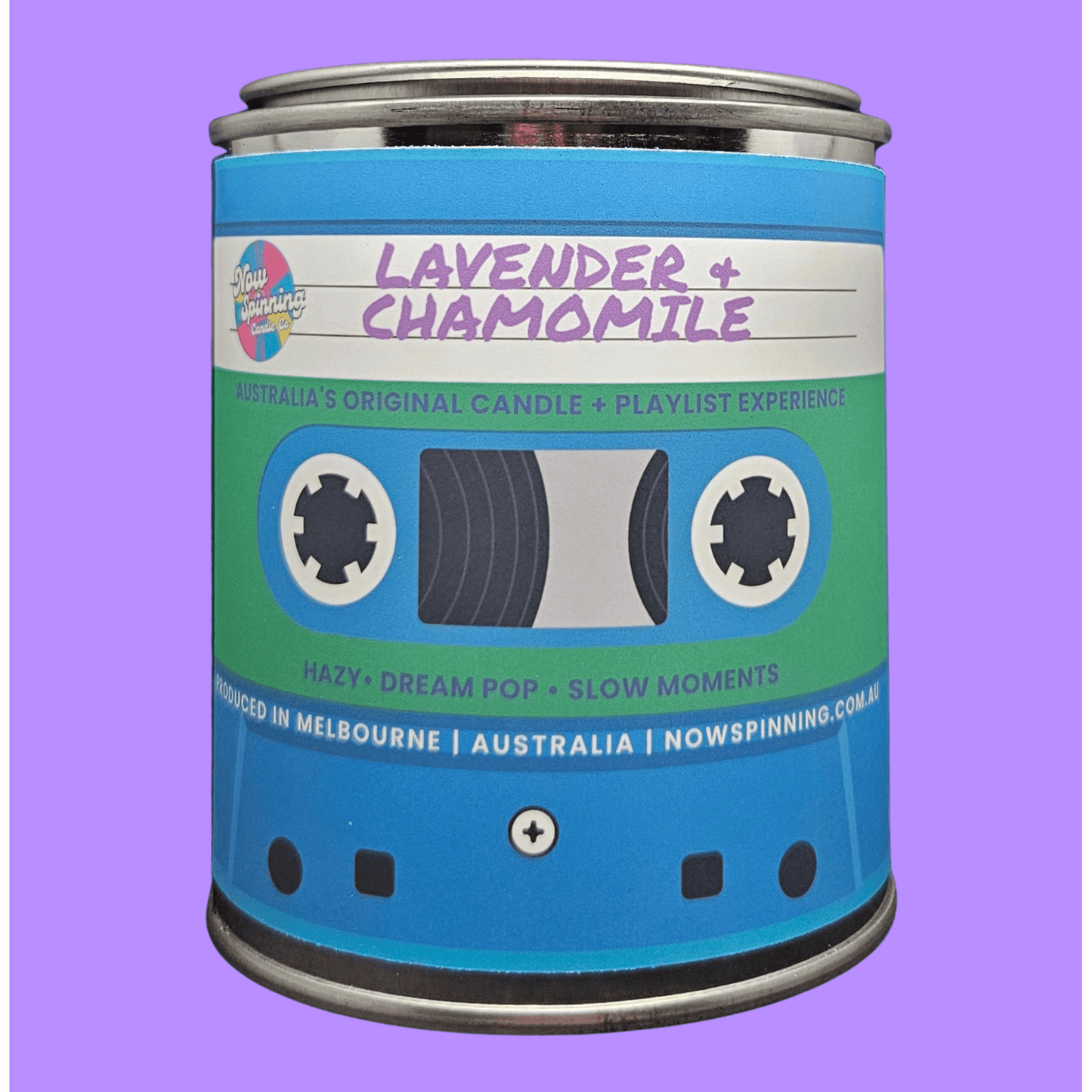 A novelty candle tin shaped like a cassette tape, labeled 'Lavender + Chamomile' by Nowspinning, set against a solid purple background.