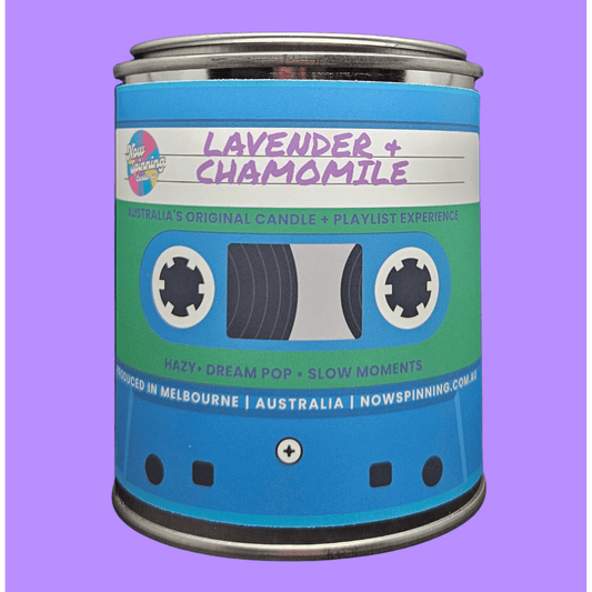 A novelty candle tin shaped like a cassette tape, labeled 'Lavender + Chamomile' by Nowspinning, set against a solid purple background.