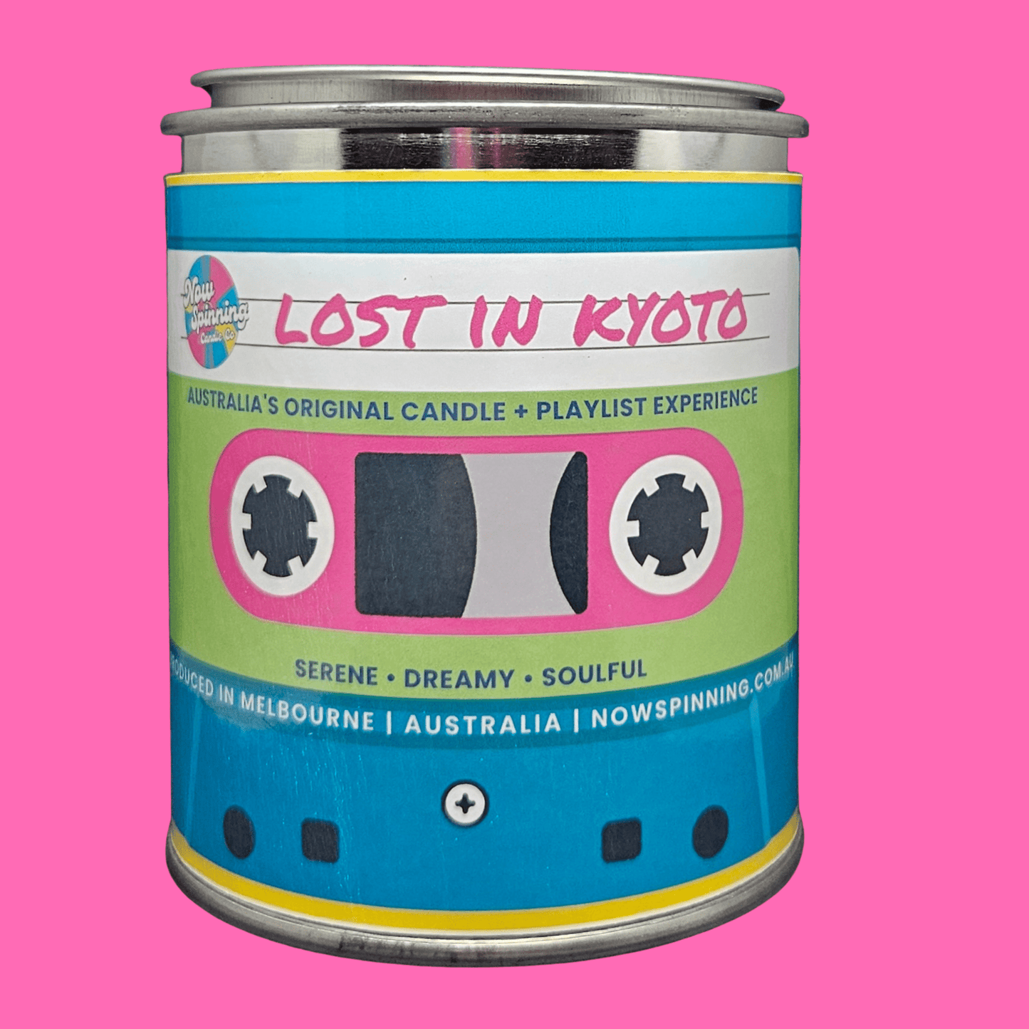 A metal tin candle labeled 'Lost in Kyoto' with a cassette tape graphic on the front, set against a solid pink background.