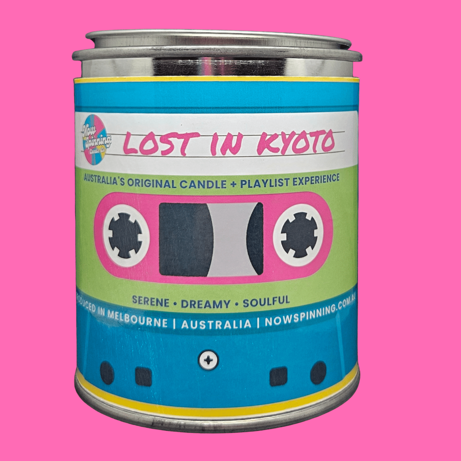 A metal tin candle labeled 'Lost in Kyoto' with a cassette tape graphic on the front, set against a solid pink background.