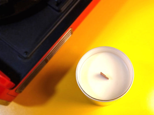 Candle on a yellow surface with a red and black object partially visible