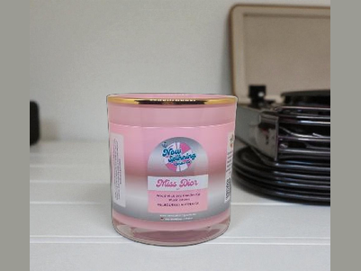 Pink candle jar with 'Miss Dior' label on a white surface
