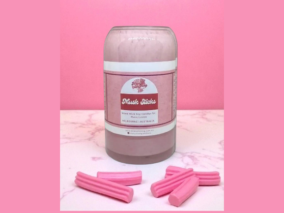 Jar of pink wax sticks with a pink background