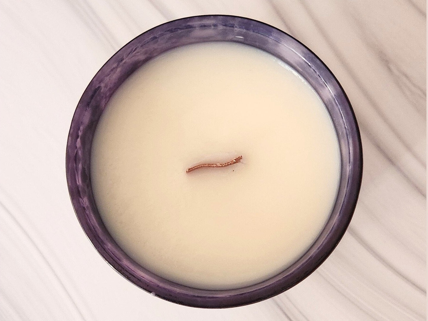 Candle with a small wood wick on top in a purple container