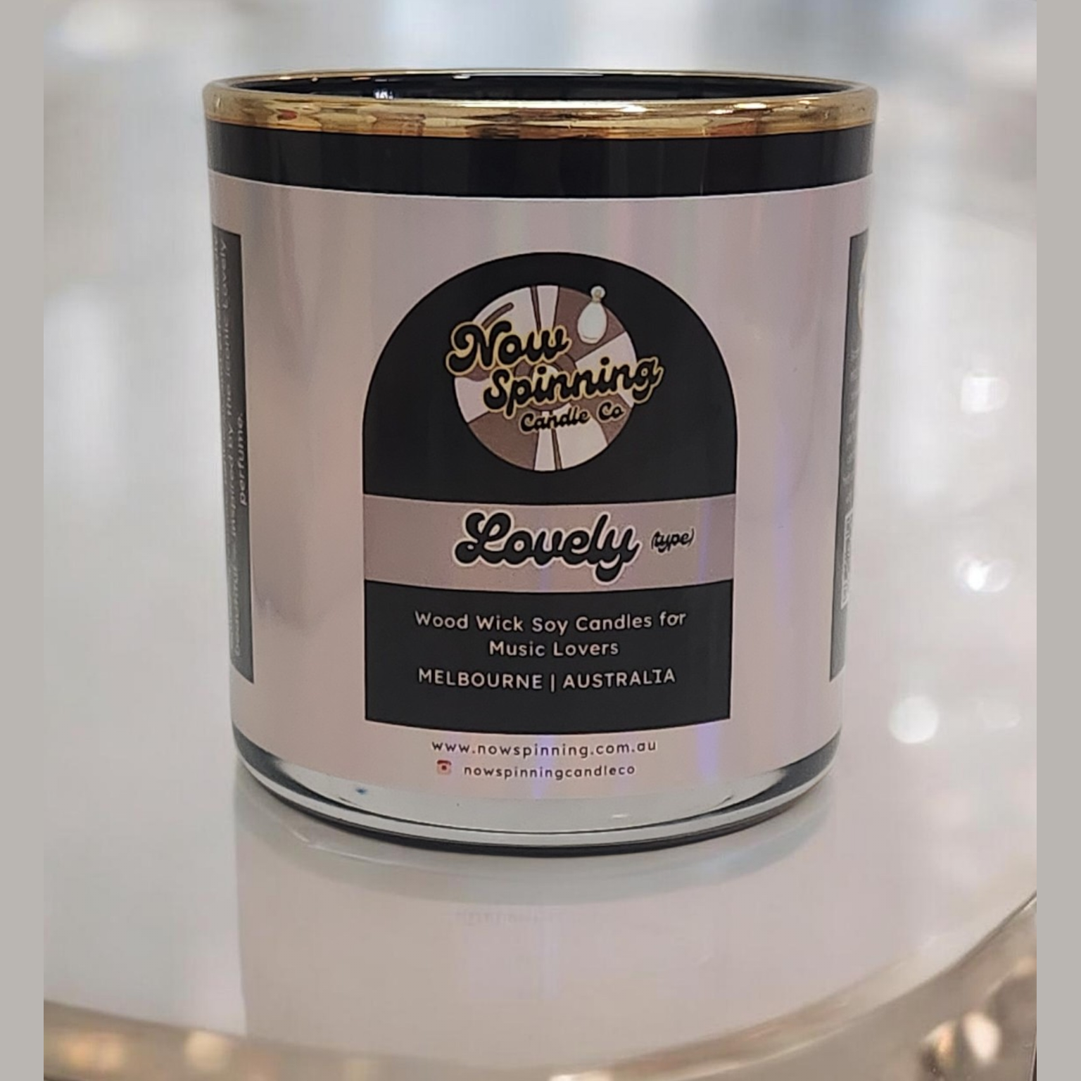 Candle in a glass jar with a label on a reflective surface