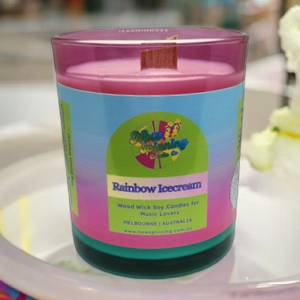 Colorful candle with a rainbow ice cream design on a white plate.