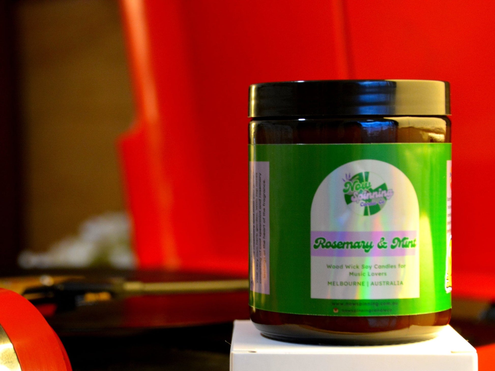 Jar of 'Rosemary & Mint' candle on a white surface with a red record player