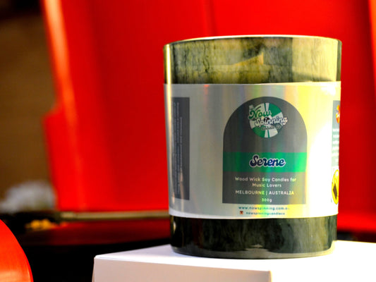 Candle in a green container with a label on a red background