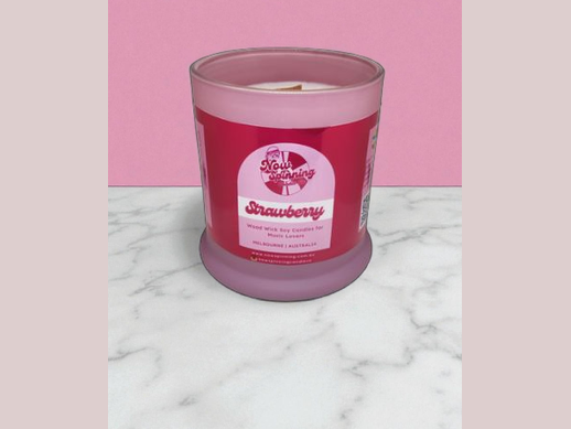 Pink candle with a label on a marble surface and pink background
