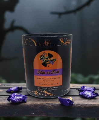 Candle with a label on a wooden surface with purple wrappers.