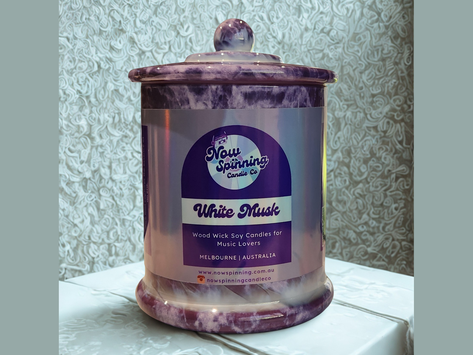 Candle jar with a label on a textured surface