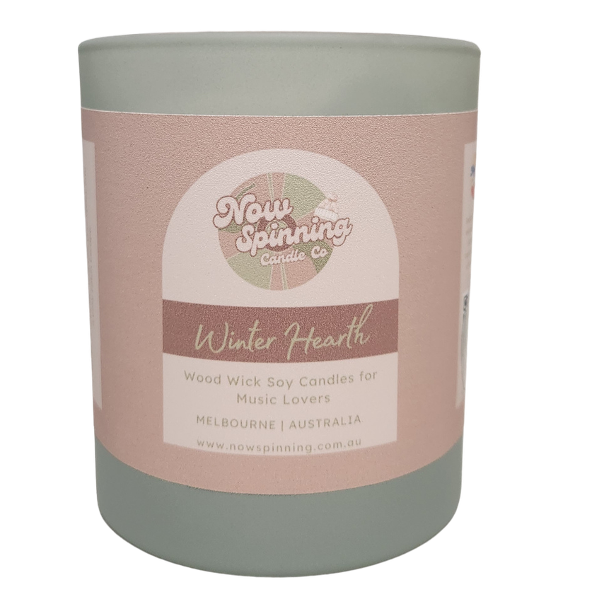 Winter Hearth wood wick soy candle by Now Spinning Candle Company featuring smoky firewood, amber and pine notes. Styled in a cosy winter setting inspired by crackling fireplaces, warm blankets and relaxing evenings at home.